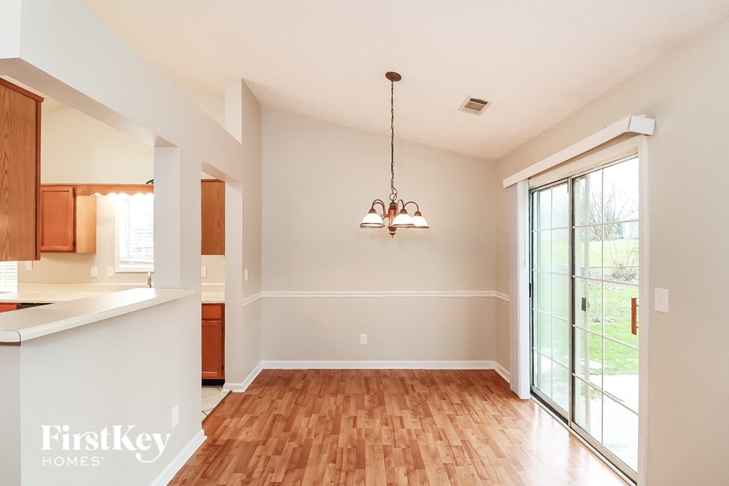 A room with wooden floors and a chandelier hanging from the ceiling.