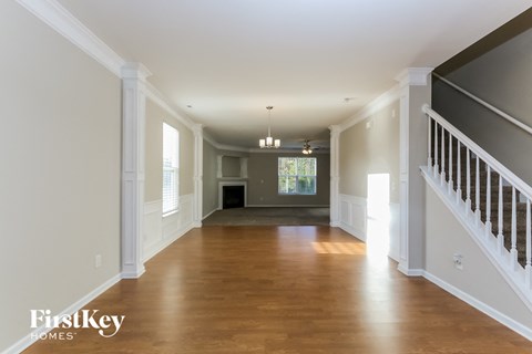 A spacious hallway with wooden floors and white walls.