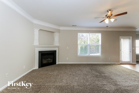 A spacious living room with a fireplace and a ceiling fan.