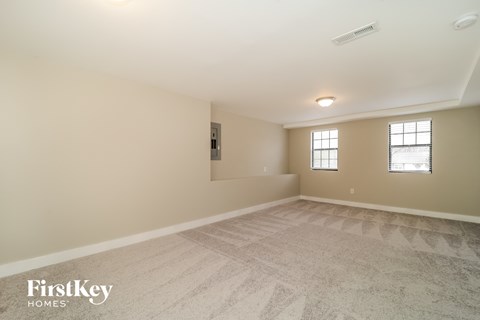 a spacious living room with beige walls and carpet and a window