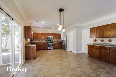 A spacious kitchen with wooden cabinets and a tiled floor.