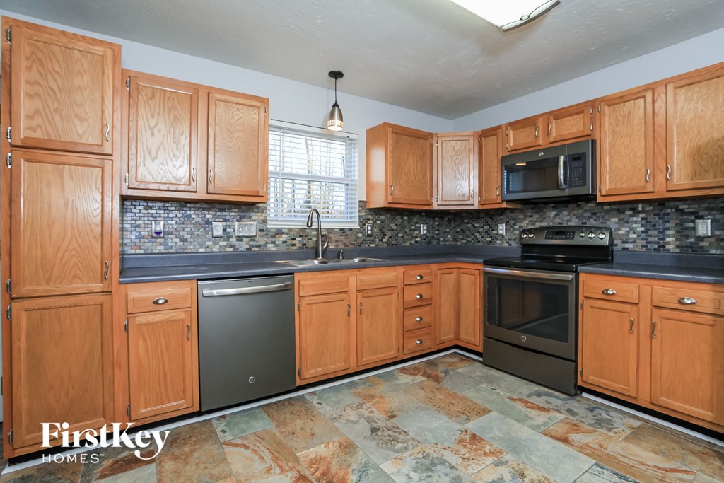 A kitchen with wooden cabinets and a stone counter top.
