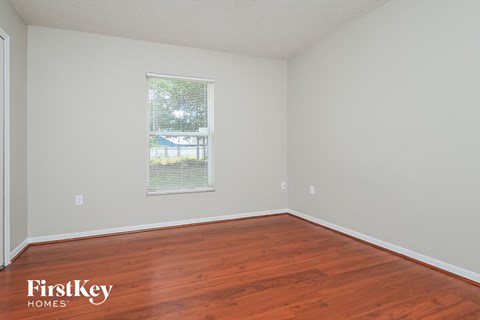 a bedroom with wood floors and white walls and a window