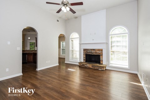 A spacious living room with a fireplace and a ceiling fan.