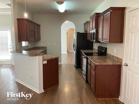 A kitchen with wooden cabinets and a black refrigerator.