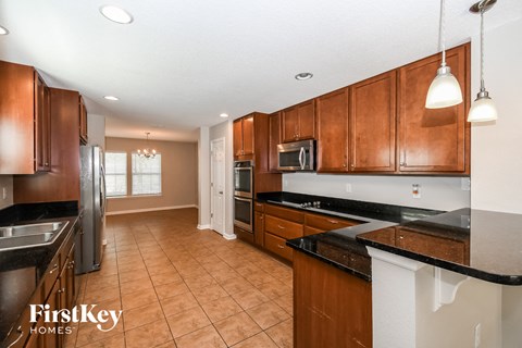 a kitchen with wooden cabinets and black counter tops and a stainless steel refrigerator