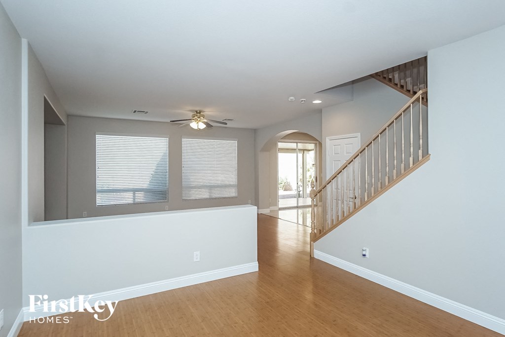 A spacious room with a staircase and a ceiling fan.