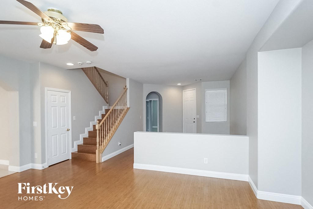 A spacious room with a staircase and a ceiling fan.