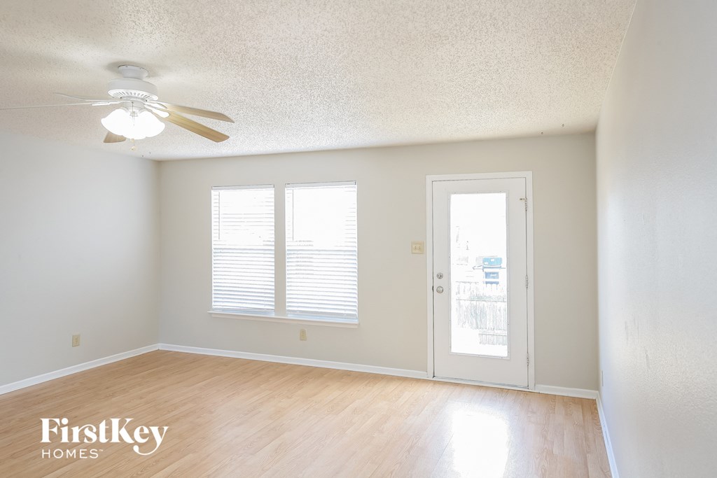 A room with a ceiling fan and a door leading to another room.
