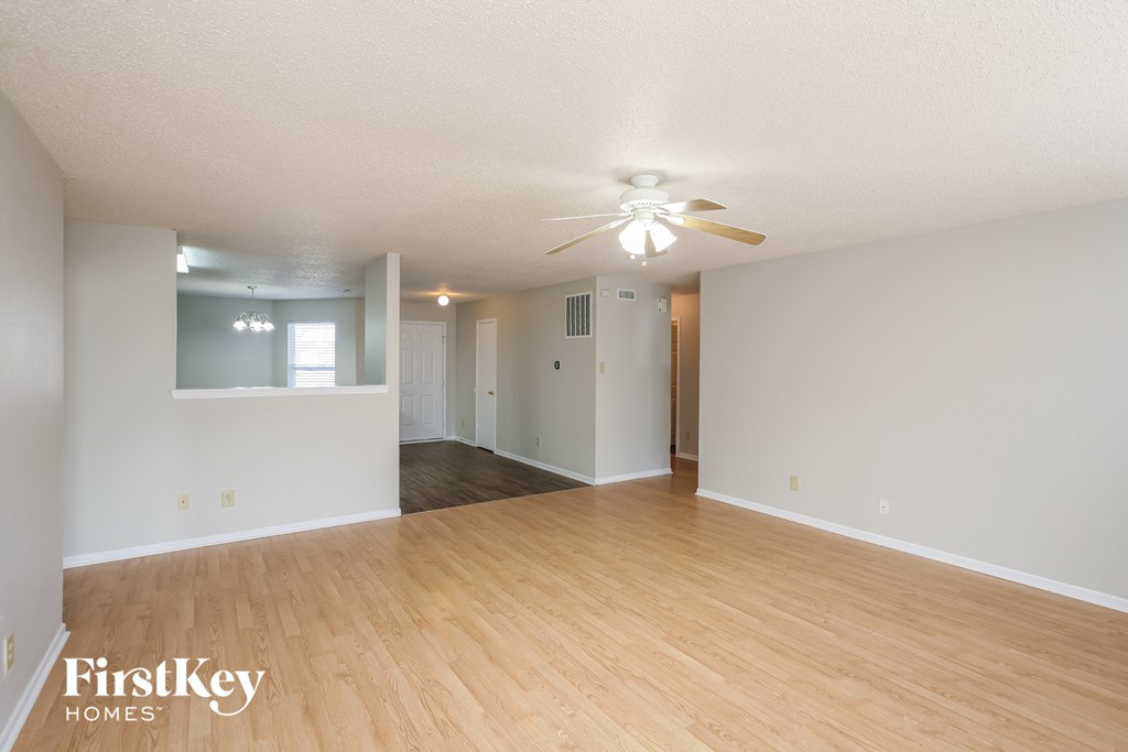 A spacious room with a ceiling fan and wooden flooring.