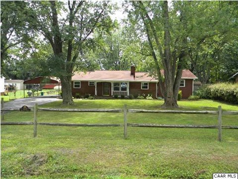 a red house with a fenced in yard and trees