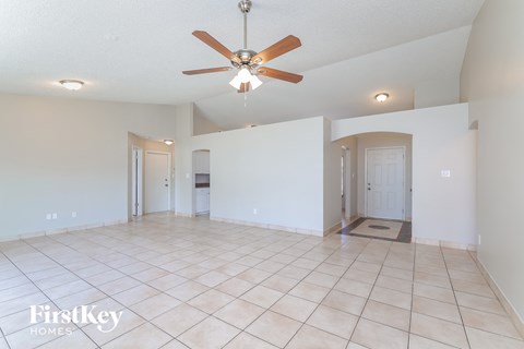 an empty living room with a ceiling fan and a tiled floor