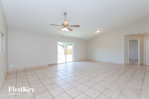 an empty living room with a ceiling fan and a tiled floor