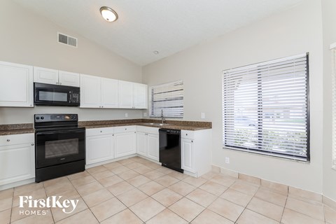 a kitchen with white cabinets and black appliances and a large window