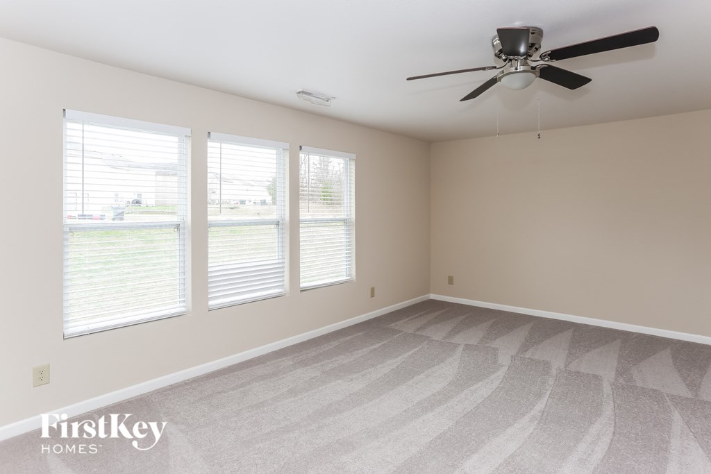 a living room with a ceiling fan and three windows