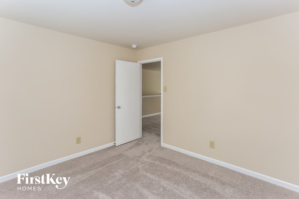 a room with a carpeted floor and a door to a closet