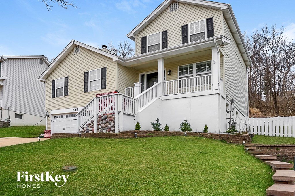 A two-story house with a white front porch and a staircase leading to the second floor.