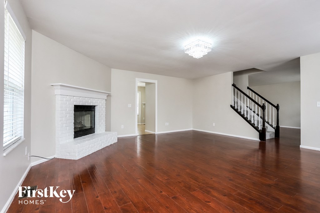 A spacious room with a fireplace and wooden floors.