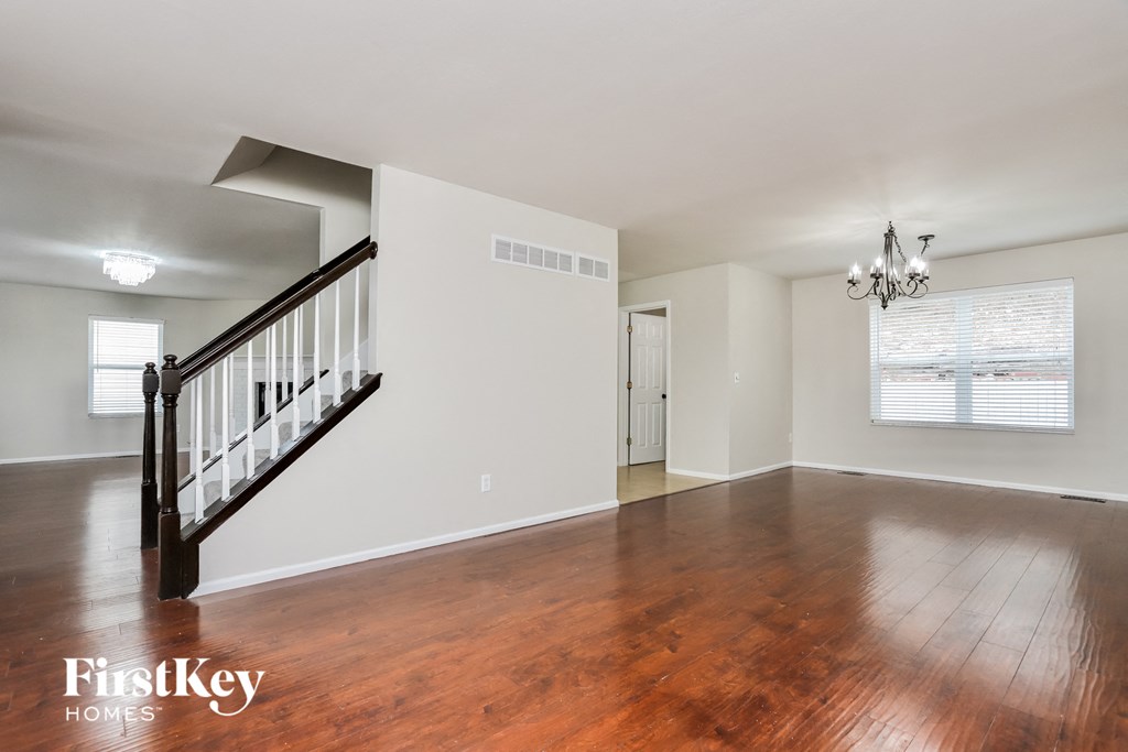 A spacious room with wooden floors and a staircase.