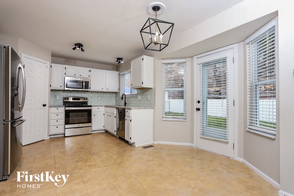 A kitchen with a refrigerator, microwave, oven, and cabinets.
