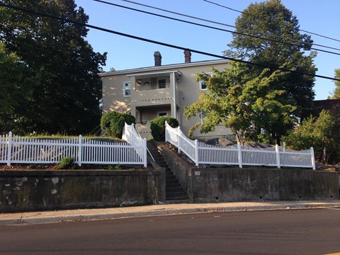 A house with a white fence and stairs leading up to it.