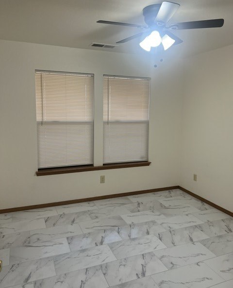 an empty room with a ceiling fan and two windows