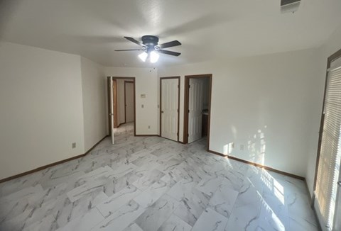 a living room with a ceiling fan and a marble floor