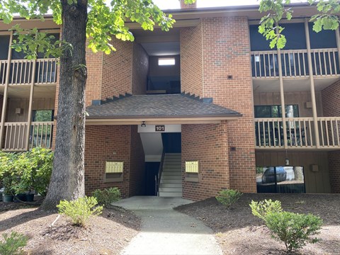 the entrance to an apartment building with a tree in front of it