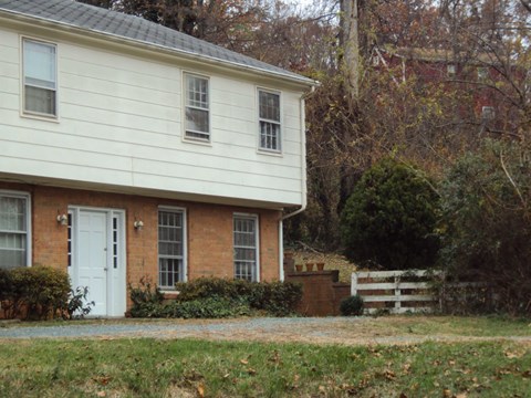 the side of a house with a white door and a brick house
