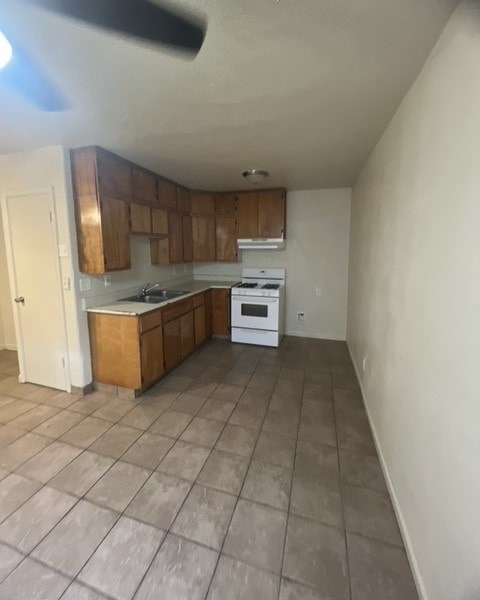 an empty kitchen with wooden cabinets and a white stove