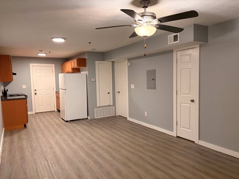A room with a ceiling fan and a white refrigerator.
