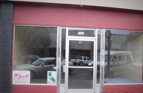 a view of the front door of a shop with cars in the window