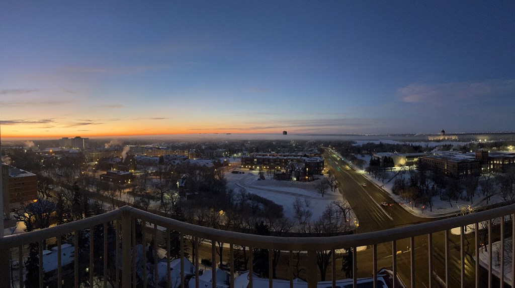 a balcony with a view of a city at sunset