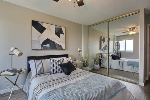 A bedroom with a large bed and a mirrored wall.
