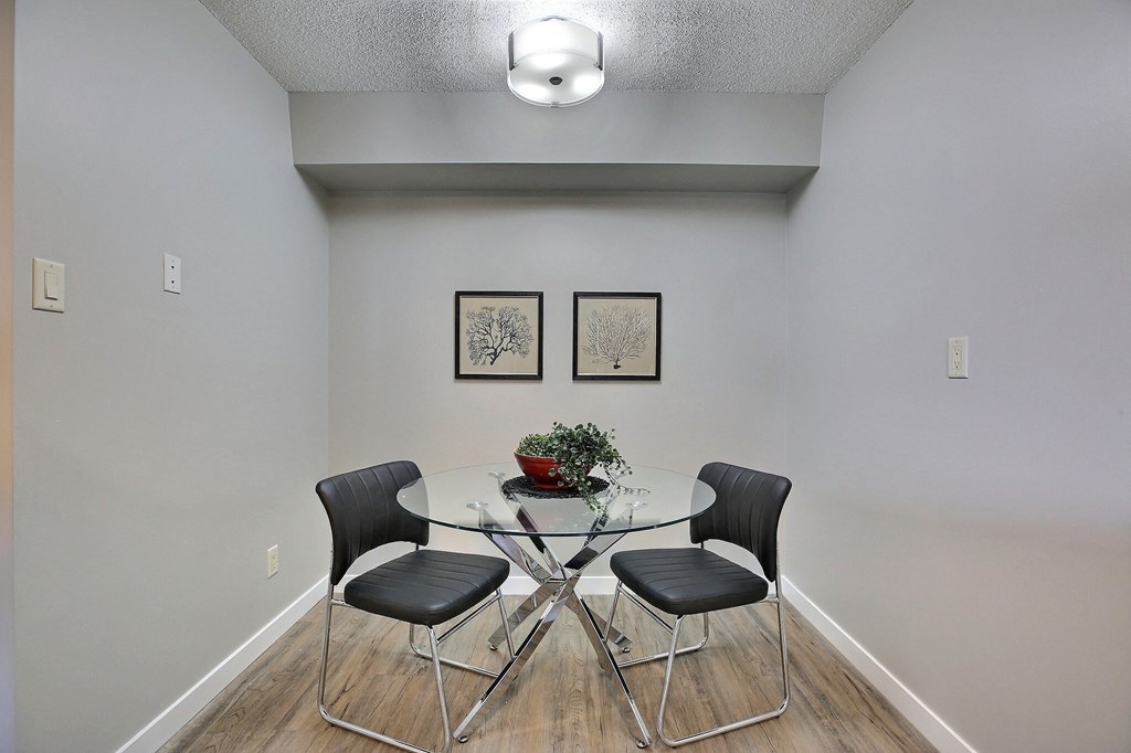an empty dining room with a glass table and chairs