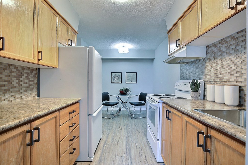 a kitchen with wooden cabinets and white appliances and a table with chairs