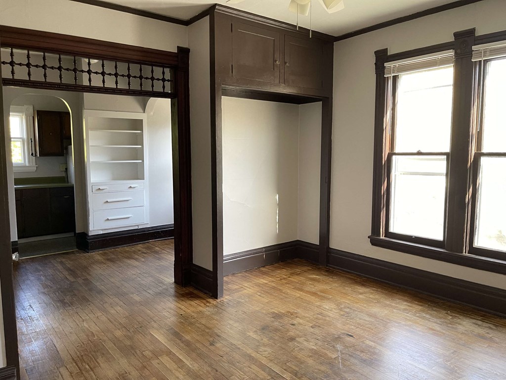 an empty living room with wood floors and a closet