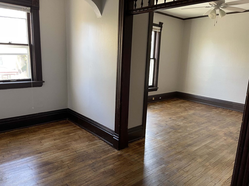 an empty living room with wood floors and a window