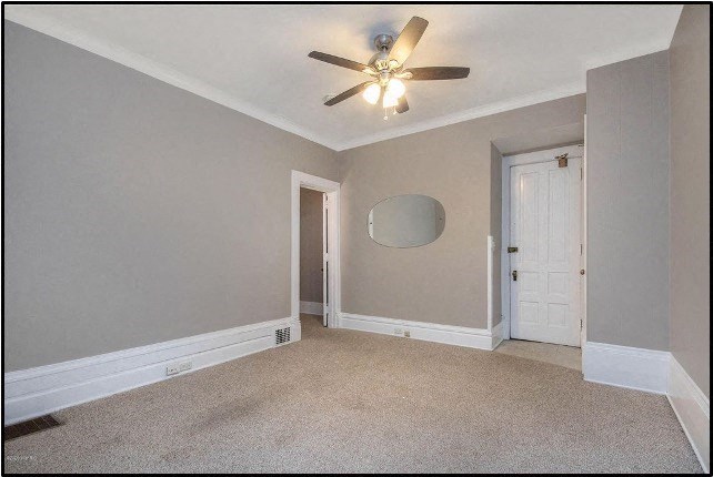 an empty living room with a ceiling fan and a door