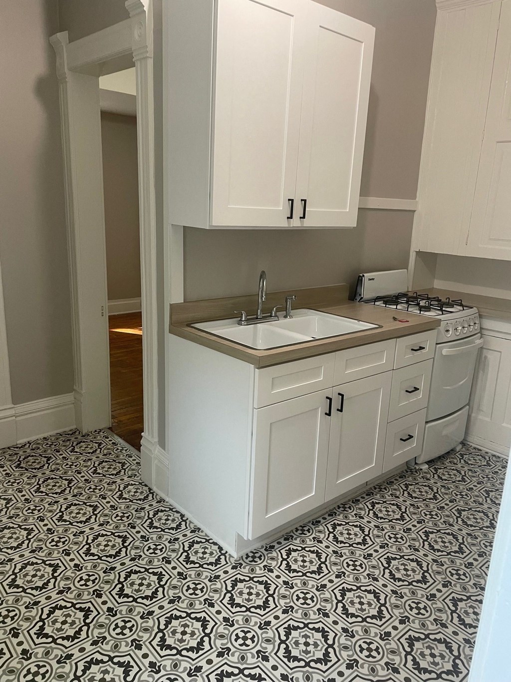 a kitchen with white cabinets and a sink and tile floor