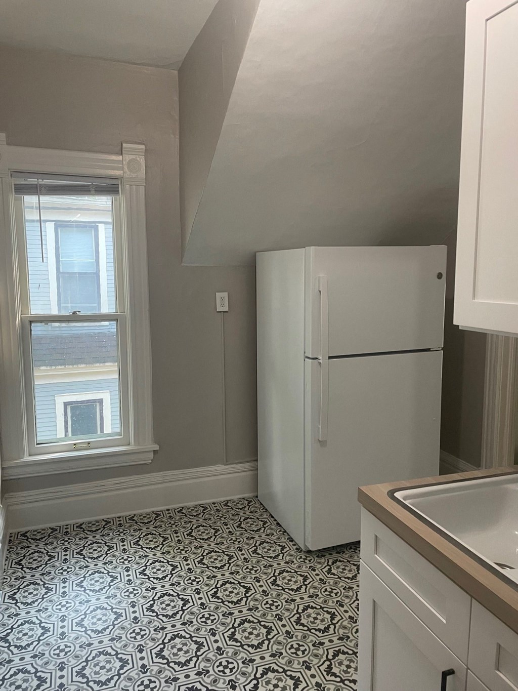 a small kitchen with a refrigerator and a window