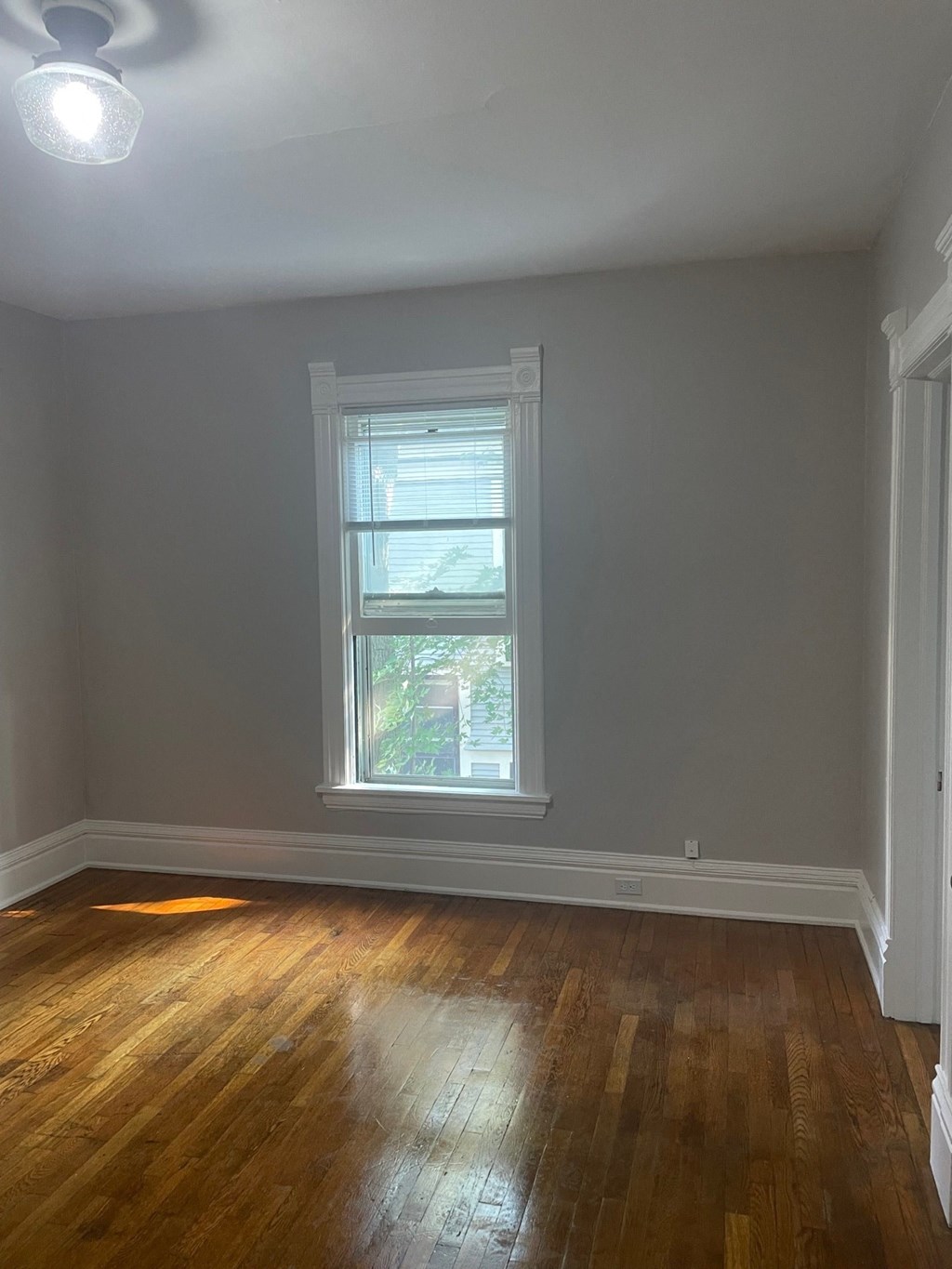 an empty room with a window and wooden floors