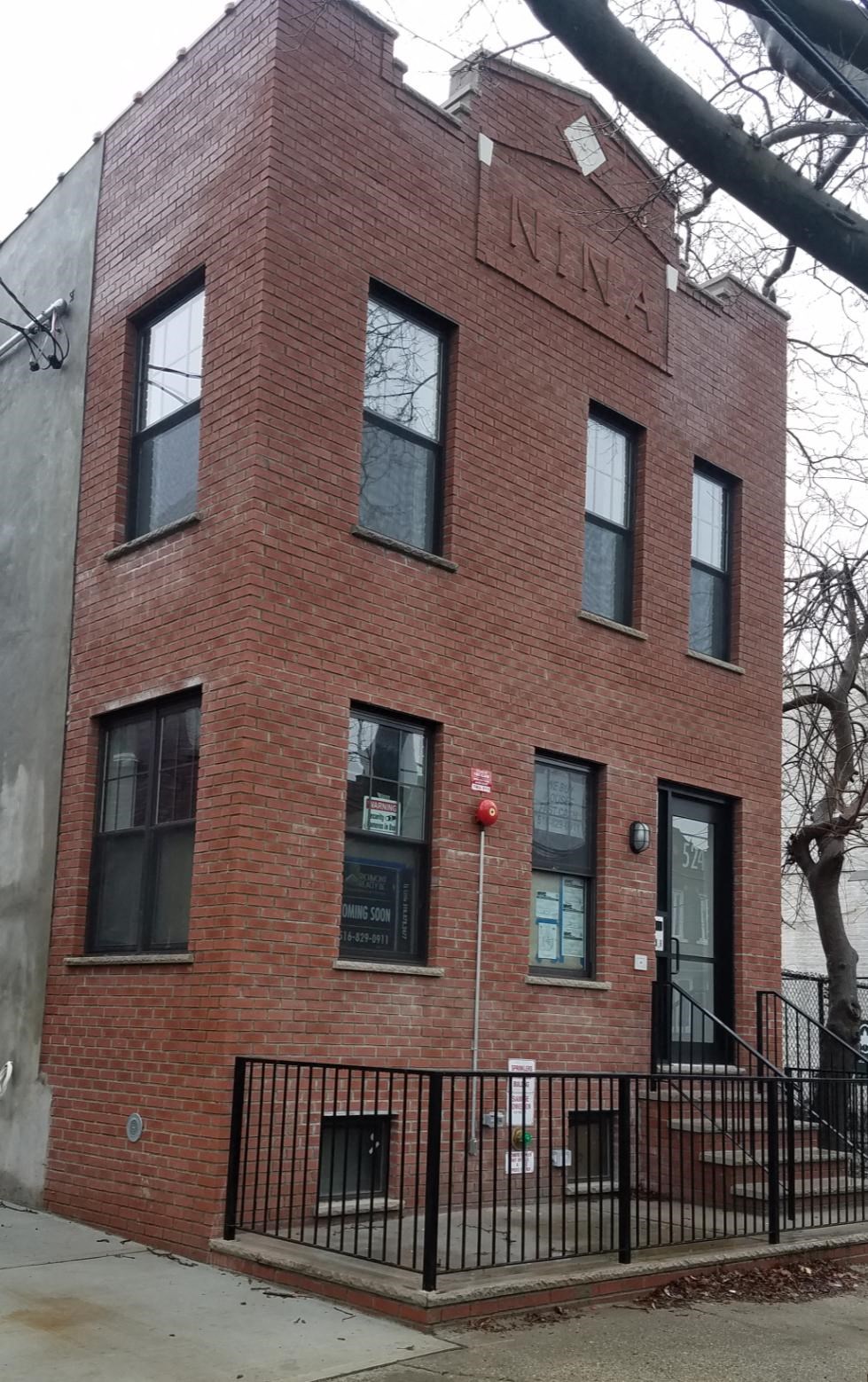A red brick building with a black iron fence in front.