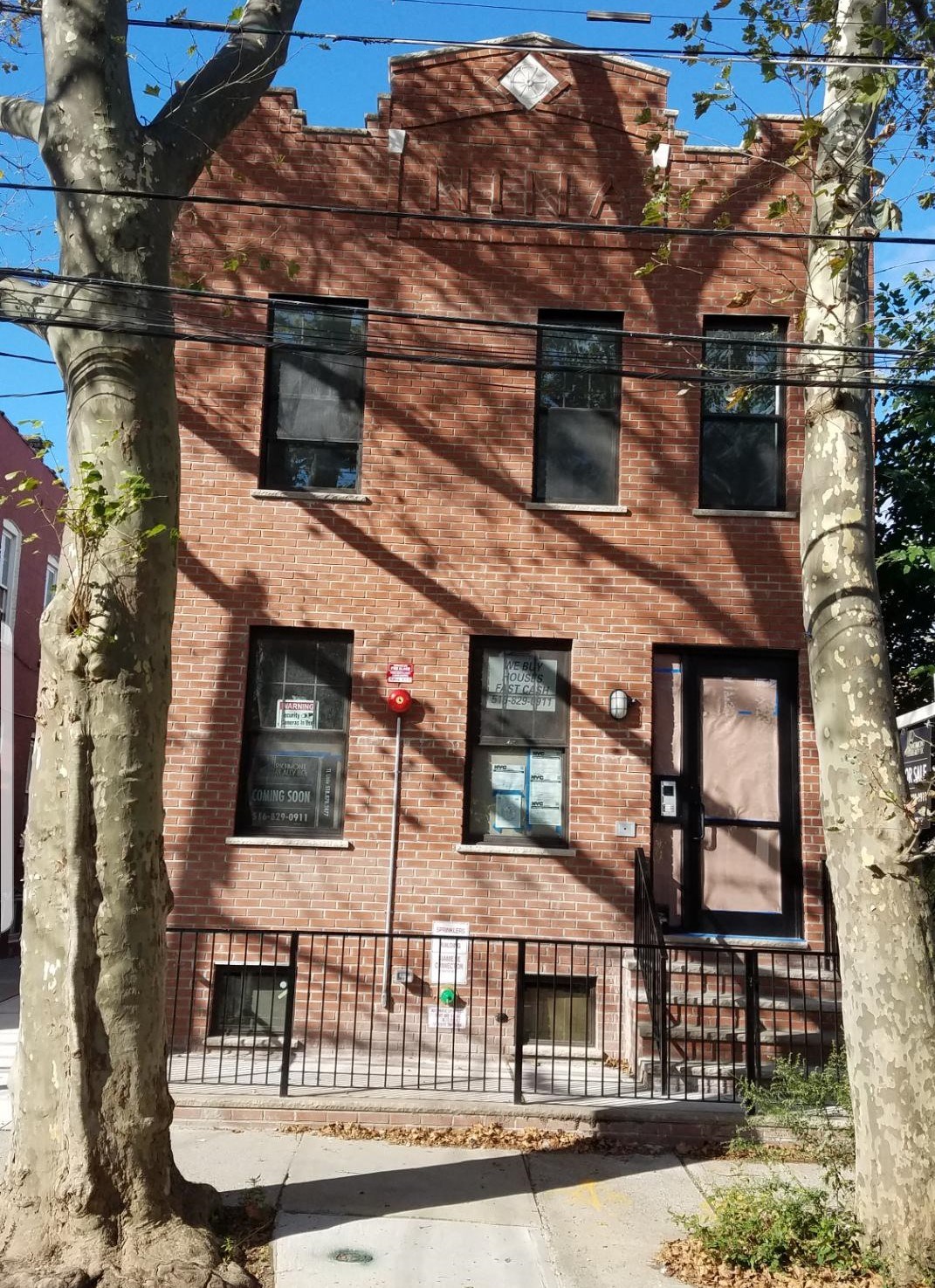 A red brick building with a black gate in front.