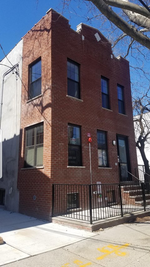 A red brick building with a black iron fence in front.