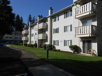 an apartment building with white siding and a sidewalk