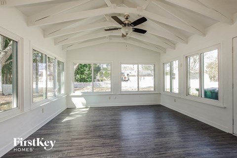 A spacious room with wooden floors and a ceiling fan.