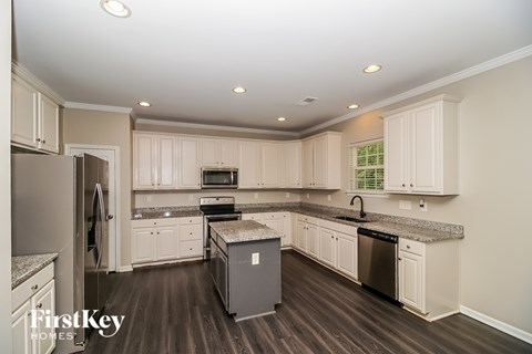 A kitchen with wooden floors and white cabinets.
