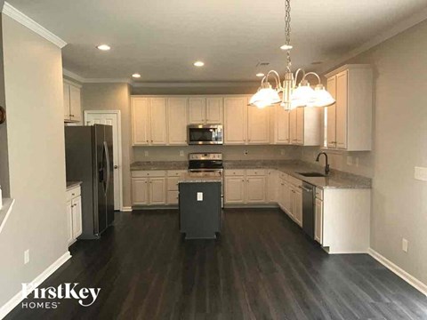 A kitchen with dark wood floors and white cabinets.