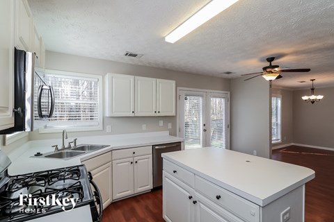A kitchen with white cabinets and a stove top oven.